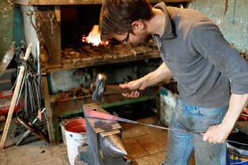 Blacksmith forging red-hot metal with hammer.