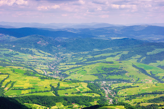 view from a mountain top in to the green valley. beautiful summer landscape of bilasovytsya village, volovets district, transcarpathia region, ukraine. gorgany ridge in the distance