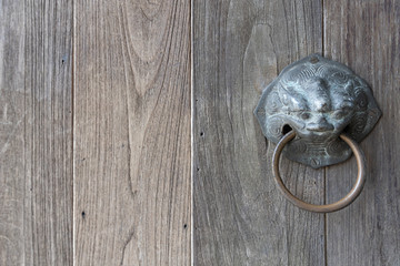 closeup of old wooden with lion or tiger shape door knob and handle ring.