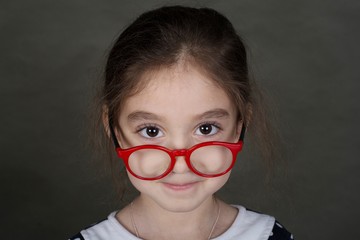 Shooting in the Studio. Portrait of a girl with glasses. The girl is wearing a dress with a white collar.