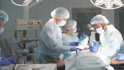 The anesthesiologist team takes care of patient lying on operation table.