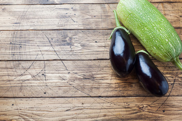 Fresh eggplant and zucchini on wooden background with copy space.