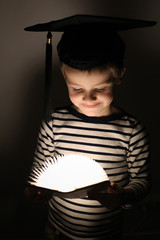Enfant qui sourit en lisant un livre illuminé