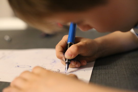 Jeune enfant qui apprend à écrire avec un stylo plume