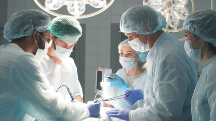 Multiracial Team of Surgeons concentrating on a patient during a heart surgery at a hospital.