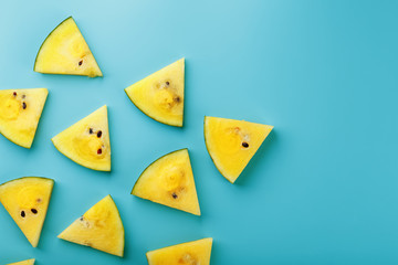 Pattern of slices of fresh yellow watermelon on a blue background. View from above. Free space