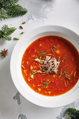 Macro Photo of Homemade Red Tomato Soup with Beef, Greens and Vegetables with Selective Focus. Rich Hot Veal Meat Broth with Tomatoes, Potatoes, Paprika in White Plate Close Up