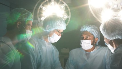 Portrait of a group of experienced surgeons in sterile surgical attire in a modern operating room.