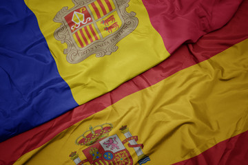 waving colorful flag of spain and national flag of andorra.