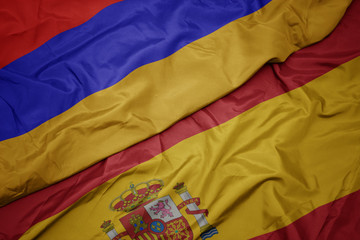 waving colorful flag of spain and national flag of armenia.