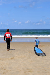 Jeune garçon qui prend une leçon de surf avec un moniteur