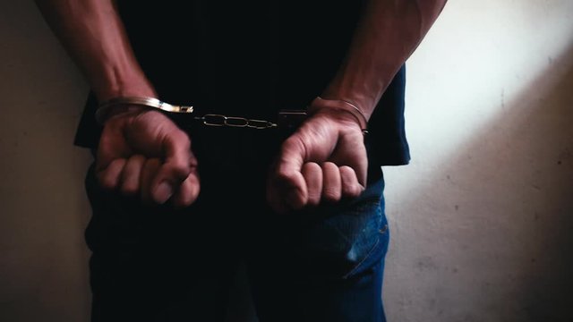Prisoner young Asian guy is cuffed, keep in custody. Bad guy is slandered by someone that he kill someone, drug dealer or break the law. Accused is one of innocent person who is slandered. copy space
