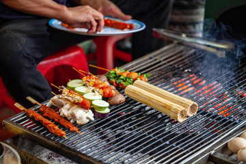 Street Cafe, North Vietnam. A man prepares seafood sticks, grilled rice in a cane on the grill