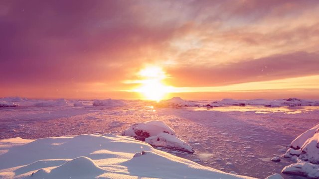 Antarctica sunrise behind glaciers silhouettes reflecting on frozen water under orange sky. Eploring beauty world. Travel, holidays, sports and recreation background. Slow motion 4K footage