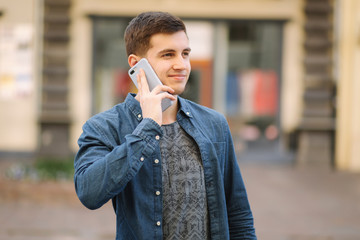 Young stylish man stand in centre of the city. Man call somebody