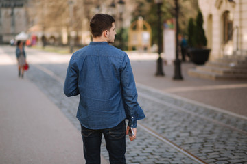 Back view of man walking in centre of the city. Blue shirt