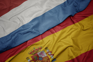 waving colorful flag of spain and national flag of luxembourg.