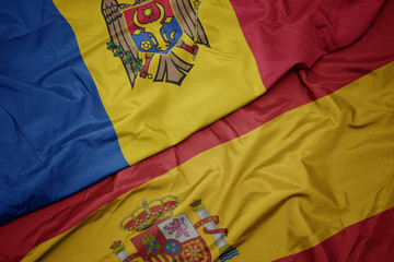 waving colorful flag of spain and national flag of moldova.