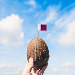 Tropical coconut with Qatar flag in the form of a toothpick in female hands.  Travel concept
