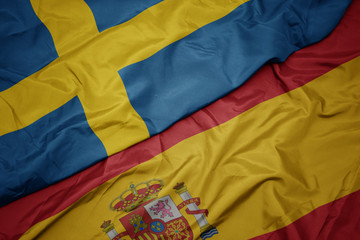 waving colorful flag of spain and national flag of sweden.