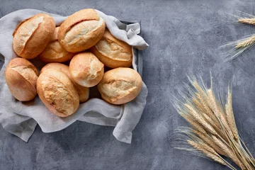 Fotobehang Bread buns in basket on rustic wood with wheat ears, top view on grey © tilialucida