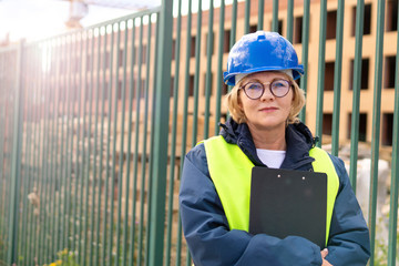 A middle-aged woman at a construction site works and checks.