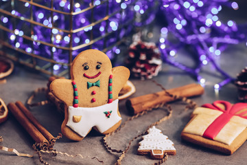 Christmas baking composition, gingerbread man on a background of purple garland bokeh, selective focus.