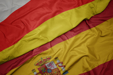 waving colorful flag of spain and national flag of south ossetia.