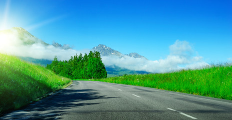 Asphalt road among the fields against the backdrop of a mountain landscape.