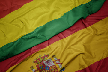 waving colorful flag of spain and national flag of bolivia.