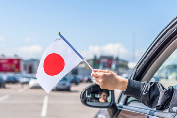 Boy holding Japan, Flag from the open car window on the parking of the shopping mall. Concept