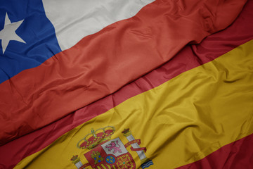 waving colorful flag of spain and national flag of chile.