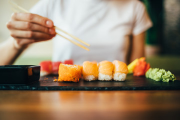 Young woman eating sushi in restaurant
