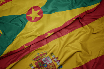 waving colorful flag of spain and national flag of grenada.