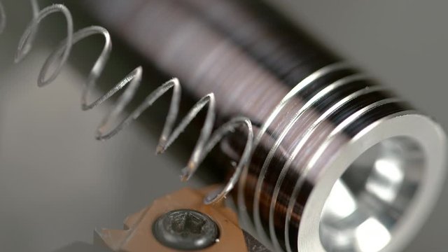 SLOW MOTION, MACRO, DOF: Sharp cutter carves a thread into a small metal rod during threading process. Detailed view of fine threading process. CNC machine threading small metal workpiece into a screw
