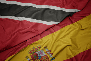 Fototapeta premium waving colorful flag of spain and national flag of trinidad and tobago.