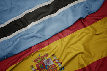 waving colorful flag of spain and national flag of botswana.