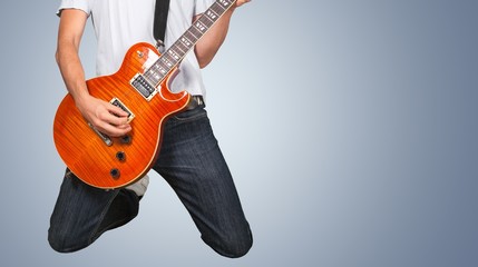Male Guitarist playing music on grey wall background
