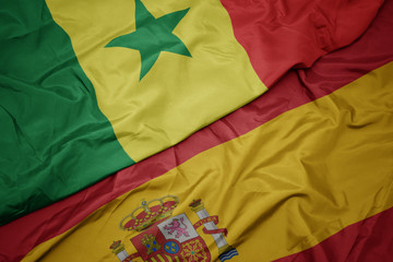 waving colorful flag of spain and national flag of senegal.