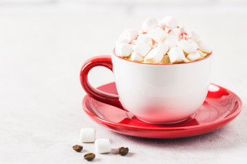 Chrismas marshmellow peppermint coffee in red cup on white marble background. Selective focus, space for text.