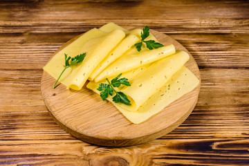 Sliced cheese and parsley on a wooden cutting board