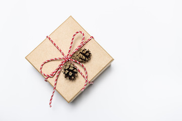 Flat lay overhead gift box with bow and pine cones on white background, copy space for your design. Minimal composition for sales, New Year or Christmas.
