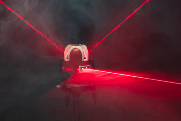 laser level tool red light beams in smoke - obrazy, fototapety, plakaty