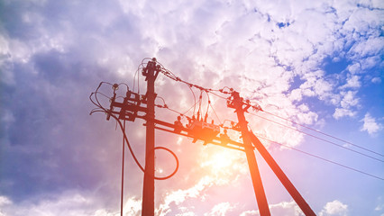 Mast transformer substation on the background of bright sun and blue sky.