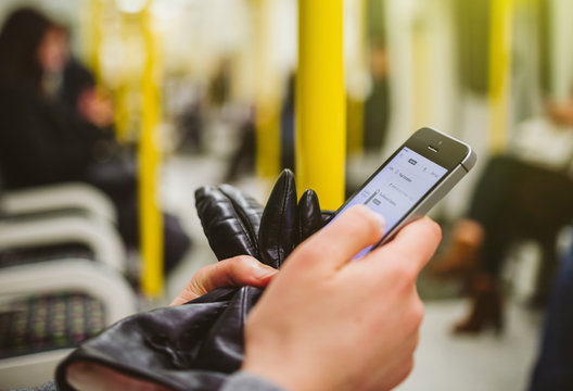 LONDON, UNITED KINGDOM - MAR 10, 2015: Woman Using Smartphone Telephone Inside Metro Tube Station Underground With Map Navigation Aplication On The Screen Open And Searching For The Next Destination 