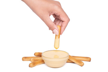 Bread stick in a female hand dipped in cheese sauce