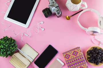 Flat lay of laptop, earphones, digital gadget, modern concept on soft pink background with copy space