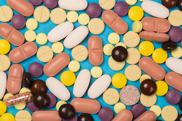 many scattered Colorful medical pills on pastel blue background
