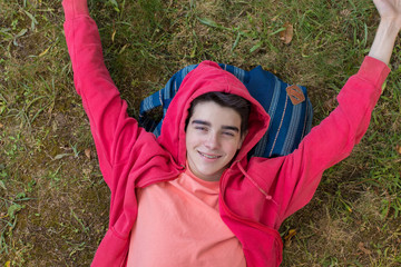 young smiling teenage girl lying in the grass of the field