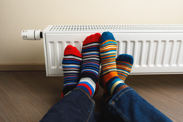 legs with colorful socks in front of heating radiator